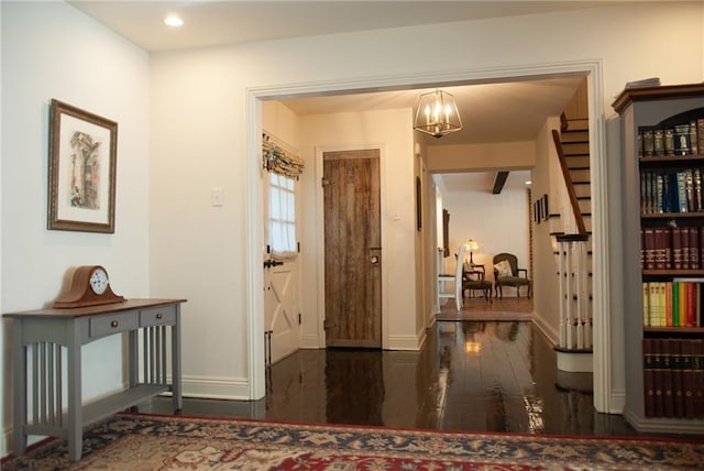 hallway with hardwood / wood-style floors, a notable chandelier, and baseboards