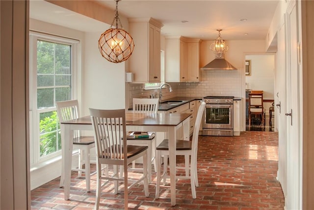 kitchen with stainless steel gas range, a sink, backsplash, dark countertops, and brick floor