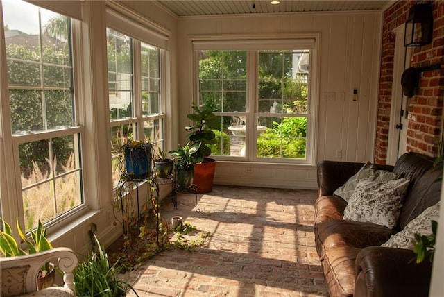 sunroom featuring brick floor, a wealth of natural light, and french doors