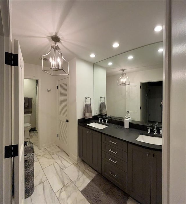 bathroom featuring toilet, recessed lighting, an inviting chandelier, and a sink