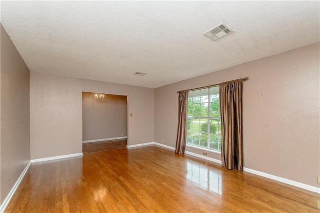 empty room with a textured ceiling, visible vents, and light wood-style floors