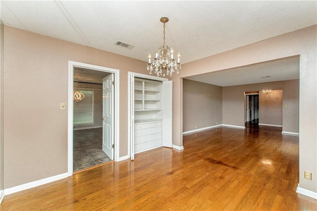 unfurnished dining area with a chandelier, baseboards, wood finished floors, and built in shelves