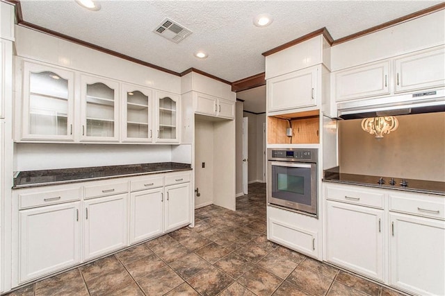 kitchen featuring ornamental molding, dark countertops, under cabinet range hood, and stainless steel oven