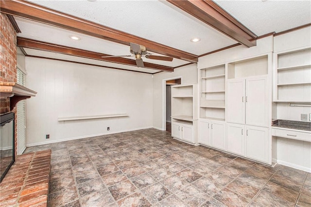 unfurnished living room with a textured ceiling, beamed ceiling, ceiling fan, a fireplace, and built in features