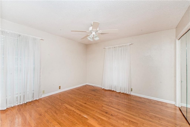 interior space featuring baseboards, light wood-type flooring, ceiling fan, and a textured ceiling