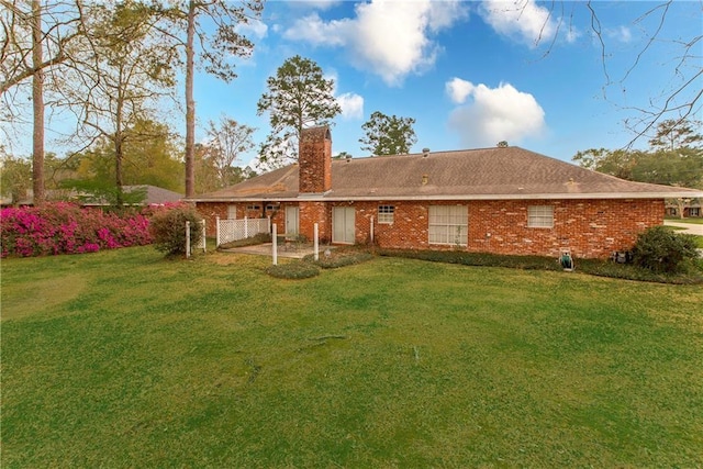 rear view of property with a chimney, brick siding, and a lawn