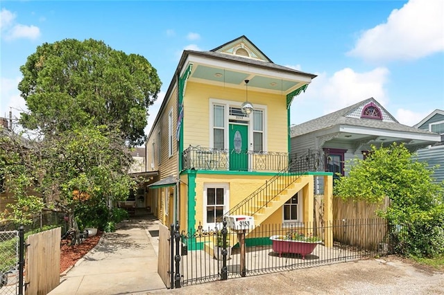 shotgun-style home with a gate, concrete driveway, stairs, and a fenced front yard
