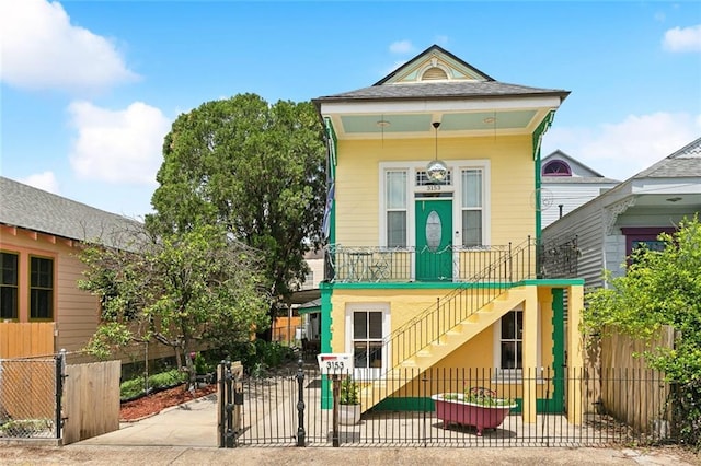 shotgun-style home with stairway, a gate, a porch, and a fenced front yard