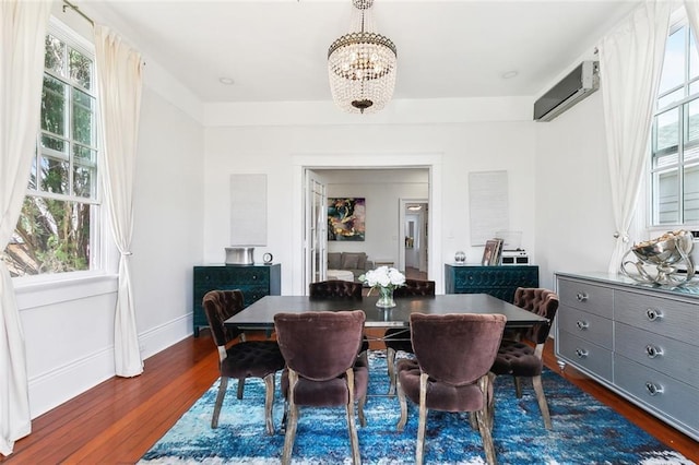 dining space with dark wood-style flooring, a chandelier, a healthy amount of sunlight, and a wall unit AC