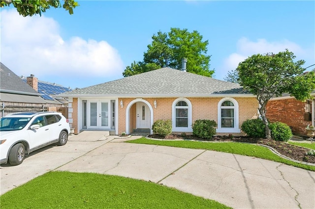 single story home featuring brick siding, roof with shingles, fence, and french doors