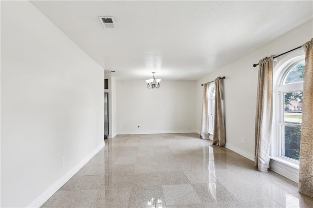 spare room featuring baseboards, an inviting chandelier, and visible vents