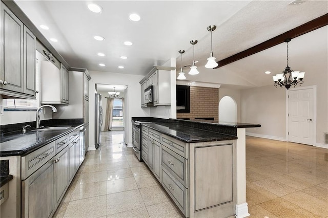 kitchen with baseboards, recessed lighting, a sink, appliances with stainless steel finishes, and a notable chandelier