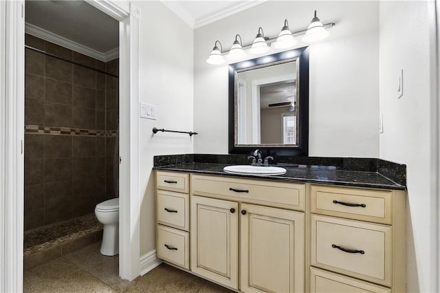 full bathroom featuring a tile shower, vanity, toilet, baseboards, and ornamental molding