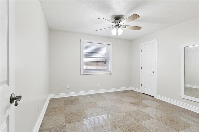 unfurnished room featuring baseboards, ceiling fan, granite finish floor, and a textured ceiling