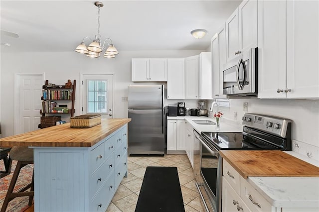 kitchen featuring a notable chandelier, a sink, appliances with stainless steel finishes, and butcher block counters