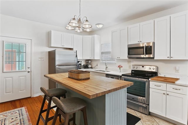 kitchen with wooden counters, a sink, appliances with stainless steel finishes, and a healthy amount of sunlight