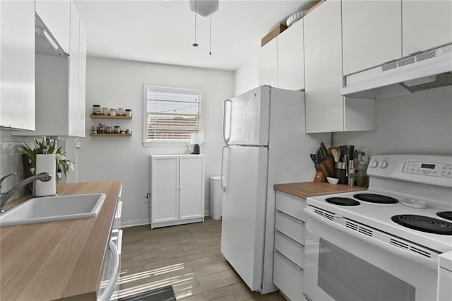 kitchen featuring a sink, under cabinet range hood, tasteful backsplash, white appliances, and white cabinets