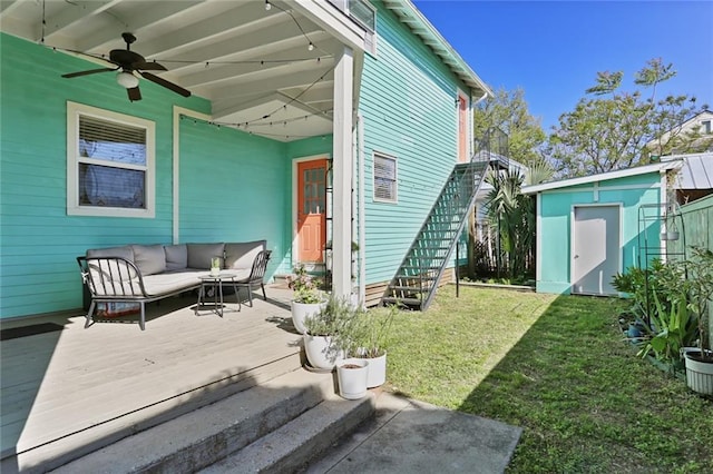 rear view of property featuring a deck, a shed, ceiling fan, a yard, and an outdoor living space