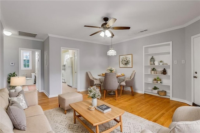 living area with visible vents, a ceiling fan, light wood-style flooring, and built in features
