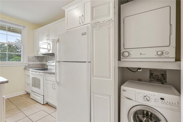 laundry room featuring light tile patterned flooring, stacked washer and clothes dryer, laundry area, and baseboards