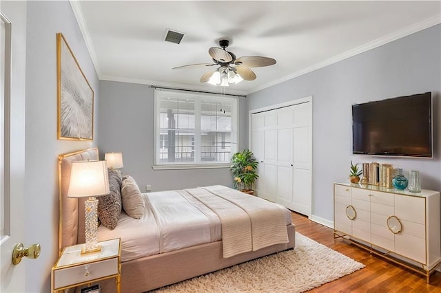 bedroom with wood finished floors, crown molding, a ceiling fan, and a closet