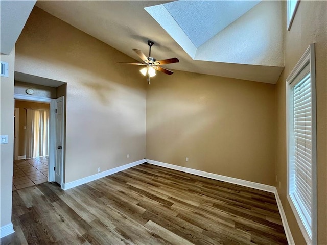 unfurnished room featuring ceiling fan, visible vents, baseboards, a skylight, and wood finished floors