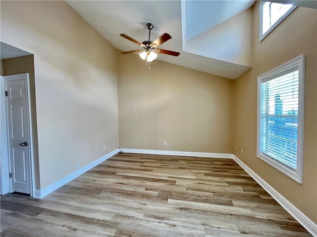 unfurnished room with baseboards, high vaulted ceiling, wood finished floors, and ceiling fan
