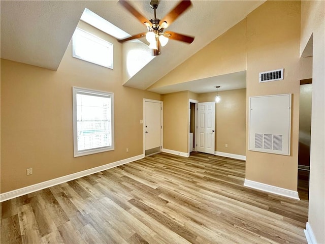unfurnished living room with visible vents, a ceiling fan, plenty of natural light, and high vaulted ceiling