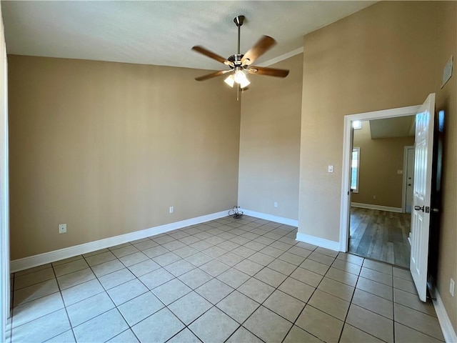 spare room featuring light tile patterned floors, a ceiling fan, and baseboards