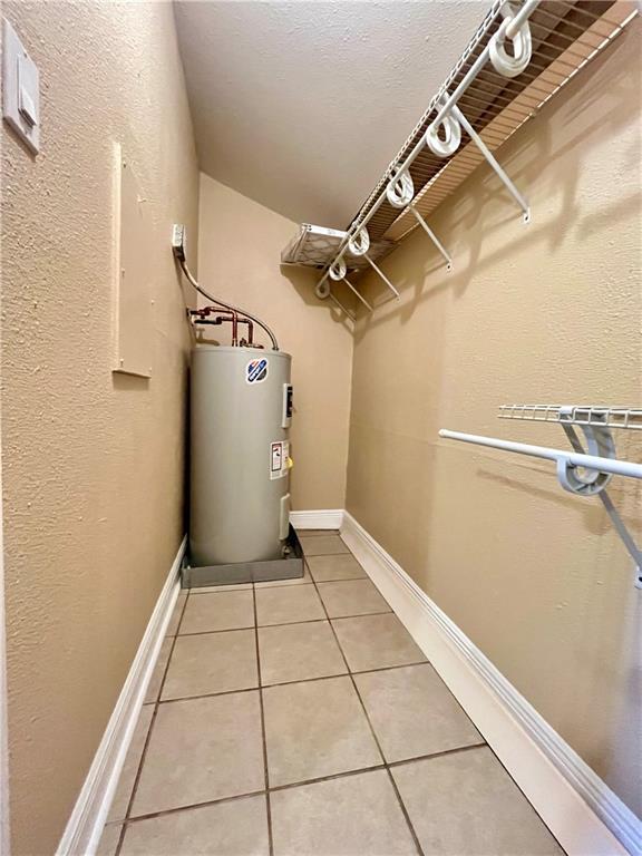 interior space with light tile patterned floors and electric water heater