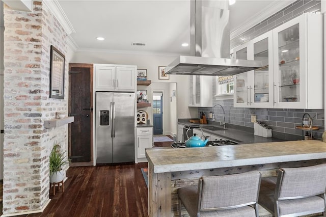 kitchen featuring a sink, island range hood, visible vents, a peninsula, and stainless steel fridge