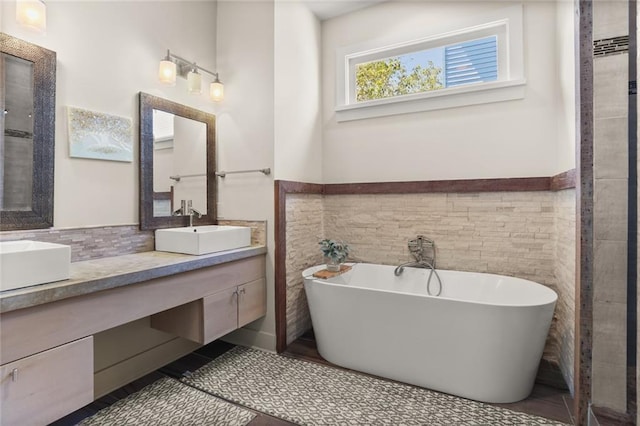 full bathroom featuring tile walls, a wainscoted wall, a soaking tub, and a sink