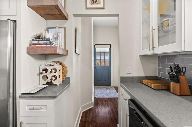 bar with decorative backsplash, black dishwasher, dark wood-type flooring, baseboards, and freestanding refrigerator