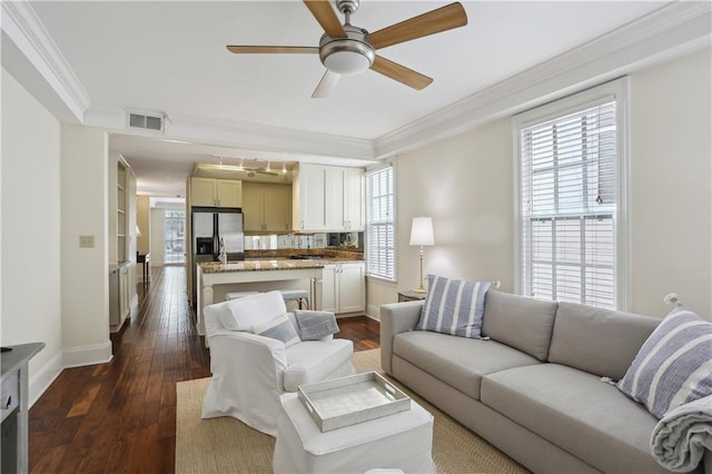 living area featuring dark wood-type flooring, visible vents, crown molding, and a ceiling fan