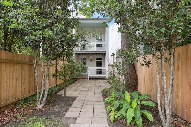 rear view of house with a fenced backyard and a balcony