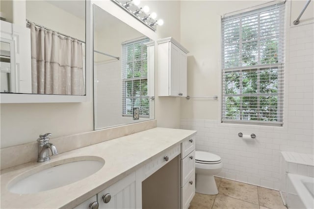 bathroom featuring tile patterned floors, tile walls, toilet, a bathtub, and vanity