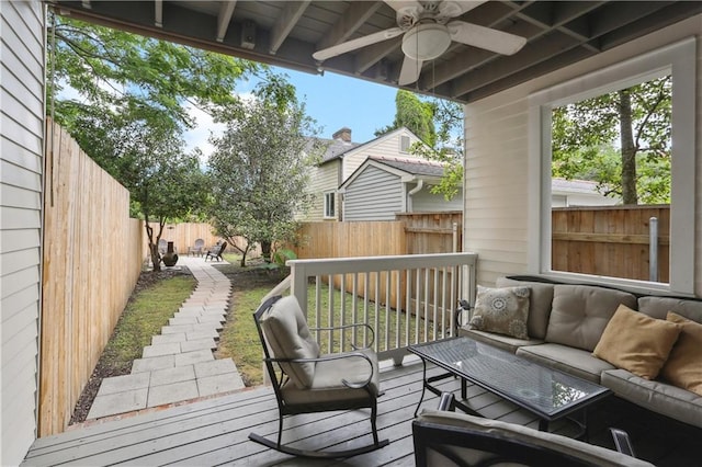wooden deck with an outdoor living space, a fenced backyard, and a ceiling fan