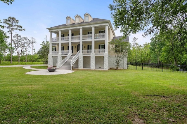 rear view of property with fence, stairs, a lawn, and a balcony