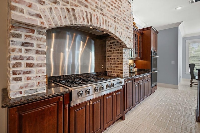 kitchen with appliances with stainless steel finishes, baseboards, visible vents, ornamental molding, and glass insert cabinets