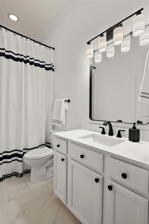 bathroom featuring vanity, ornamental molding, marble finish floor, curtained shower, and toilet