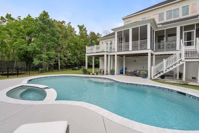 view of pool featuring fence, stairs, a pool with connected hot tub, a sunroom, and a patio