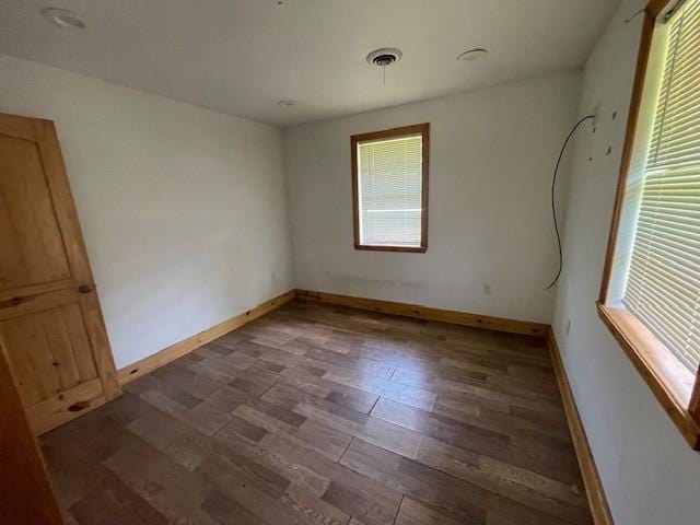 spare room with baseboards and wood finished floors