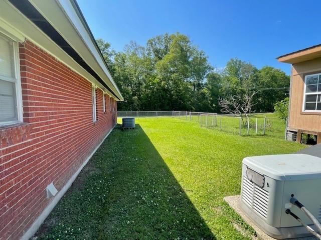 view of yard with central AC and fence