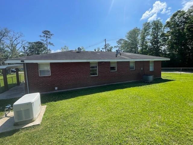 back of property with fence, a yard, and brick siding