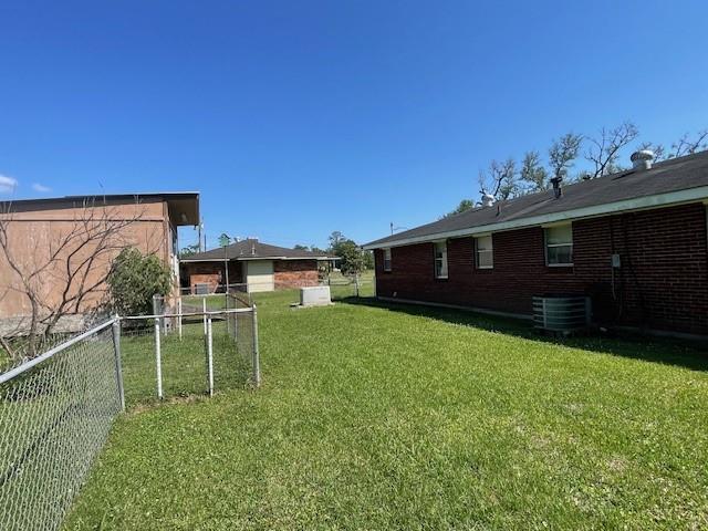 view of yard featuring fence and central air condition unit