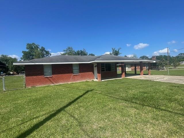 ranch-style house with a front yard, driveway, an attached carport, and fence