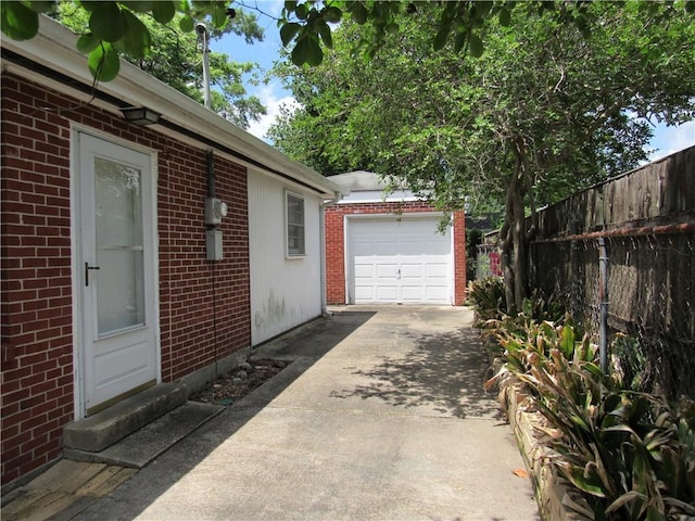 6735 W Magnolia Blvd, Harahan, LA 70123 - view of home's exterior with fence, brick siding, a garage, an outbuilding, and concrete driveway