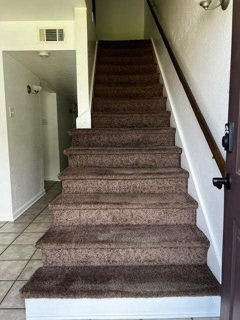 staircase with baseboards, visible vents, and tile patterned flooring