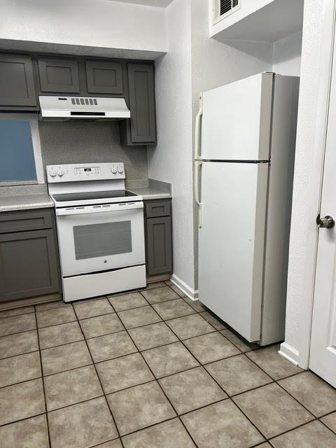 kitchen featuring light tile patterned floors, gray cabinets, white appliances, light countertops, and extractor fan