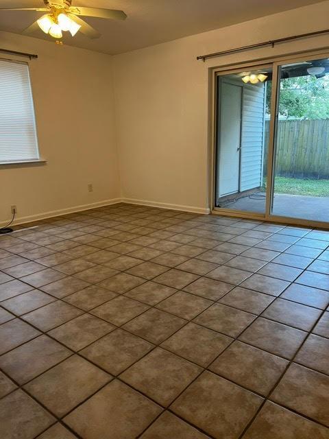 empty room with a ceiling fan, tile patterned flooring, and baseboards